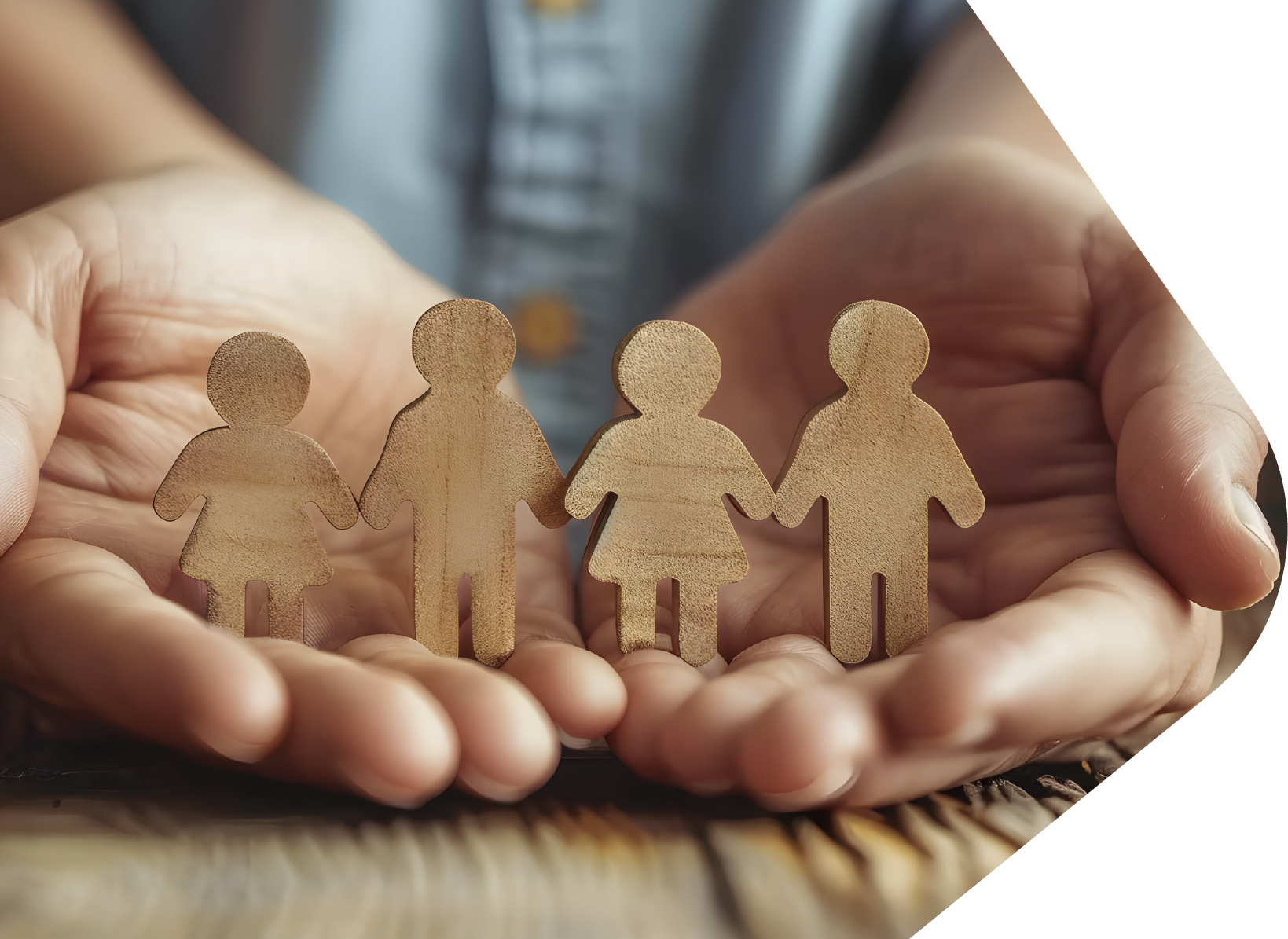 Small cut our paper people chain stands on two open palms which rest on a wooden table top